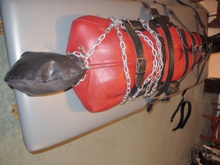 Doublerubber Hooded Catsuited Strapped To The Bondage Table - Double-rubber hooded, and leather catsuited, we watch as karina is tightly strapped down onto the bondage table.  Her upper body is wrapped in steel chains and she struggles to move even the slightest in her tight bondage.
having the outer layer of the hood zipped makes breathing a considerable challenge.

important:  please not that the video goes black from 5m38s to 6m 20s.  This is not a fault.  At the time, I was using a hand-held camera, and to allow me to fasten the second layer of karina's hood (which was very tight) I had to put down the hand-held camera).  The camera output was included in the final version so that you could hear karina's vocals as I completed her bondage.